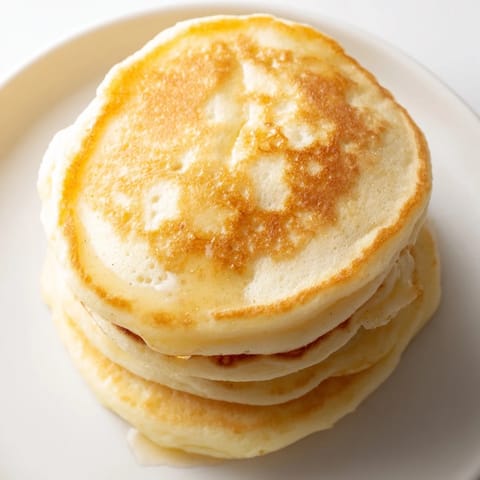 Fluffy cottage cheese pancakes piled high, with fresh berries and a pat of butter melting on top.
