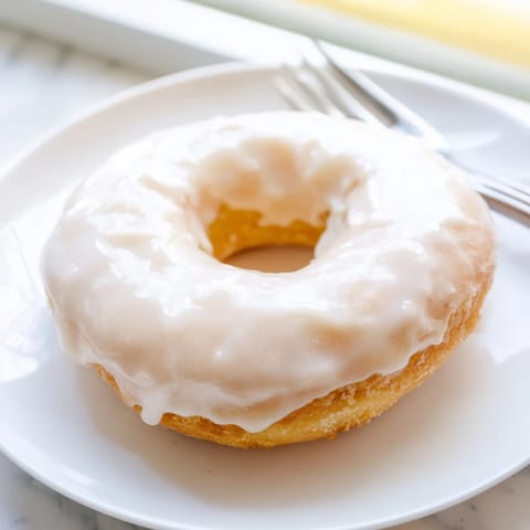 Warm, glazed yeast donuts glistening with vanilla, inviting texture and a sweet aroma.