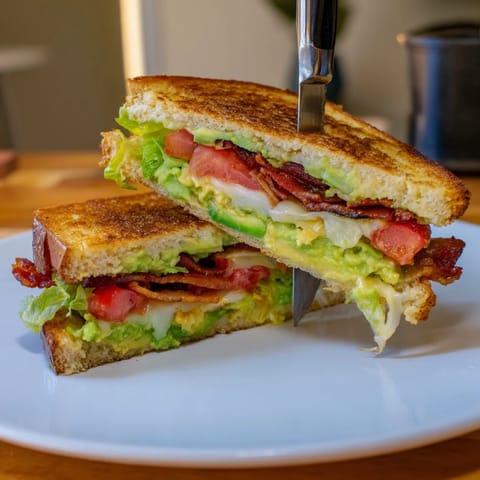 Warm, buttery sourdough sandwich filled with crispy bacon, ripe avocado, and juicy tomato for a comforting lunch.