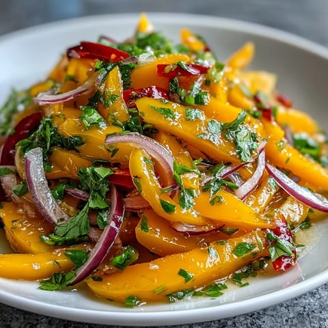 Freshly tossed Refreshing Mango Salad with Lime Dressing topped with cilantro, paired with grilled shrimp on a rustic wooden table for a light summer lunch.