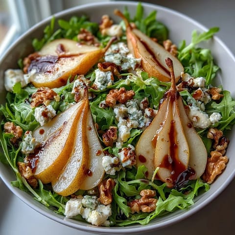 Tossed Arugula and Pear Bowl salad drizzled with balsamic dressing, served on a white plate.