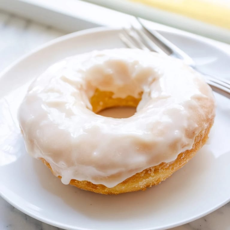 Warm, glazed yeast donuts glistening with vanilla, inviting texture and a sweet aroma.
