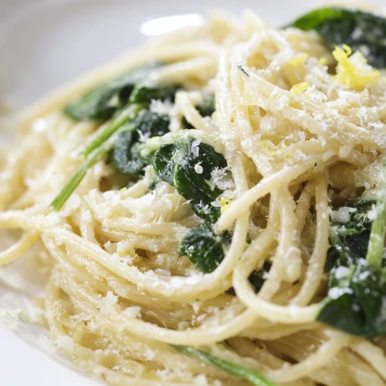 A close-up of creamy lemon spinach spaghetti, highlighting the velvety sauce clinging to al dente pasta and wilted spinach.