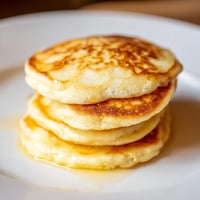 Golden-brown cottage cheese pancakes are stacked, ready to be drizzled with syrup for breakfast.
