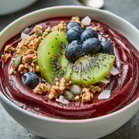 A vibrant Beet and Berry Smoothie Bowl topped with crunchy granola, fresh kiwi, and pumpkin seeds for a healthy breakfast.